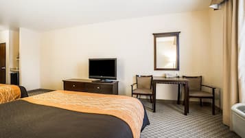 Une chambre d’hôtel comprenant un lit, un bureau, une chaise, une télévision et un miroir.