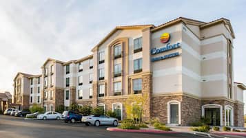 Ein Comfort Inns Suites Hotel mit modernem Design, das mehrere Balkone und einen Parkplatz mit einigen Autos zeigt.