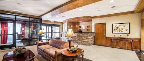 A lobby with a sofa, two tables, a stone fireplace, and a reception desk.
