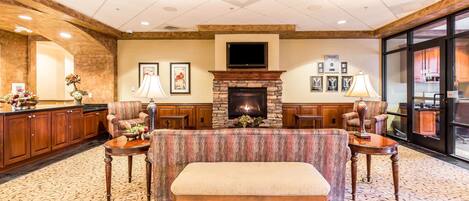 A lobby with a stone fireplace, seating area, and a bar.