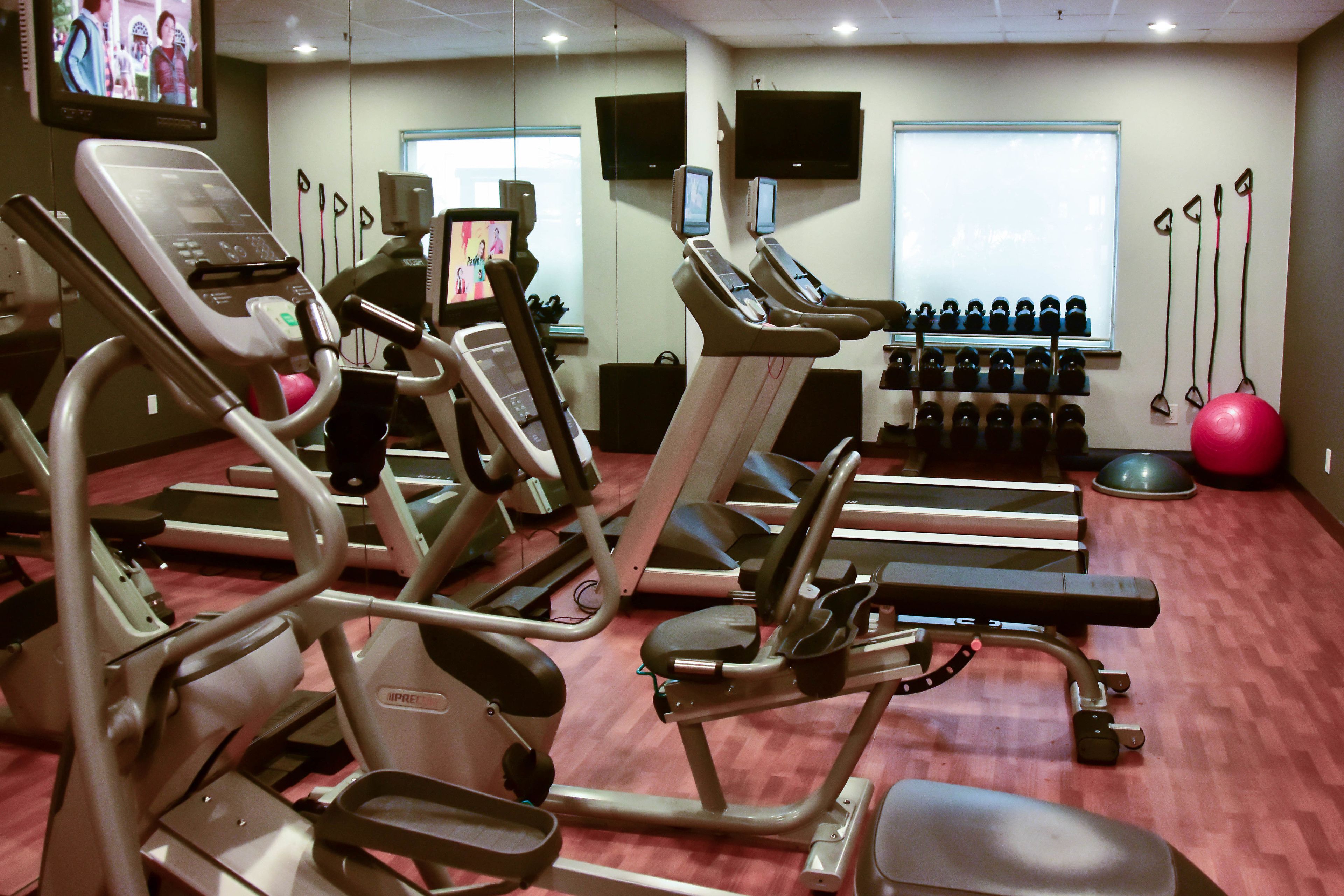 Un gimnasio con cintas de correr, elípticas y pesas libres.