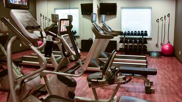 Un gimnasio con cintas de correr, elípticas y pesas libres.