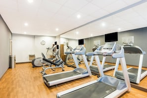 A gym with treadmills, exercise bikes, and a mirrored wall.