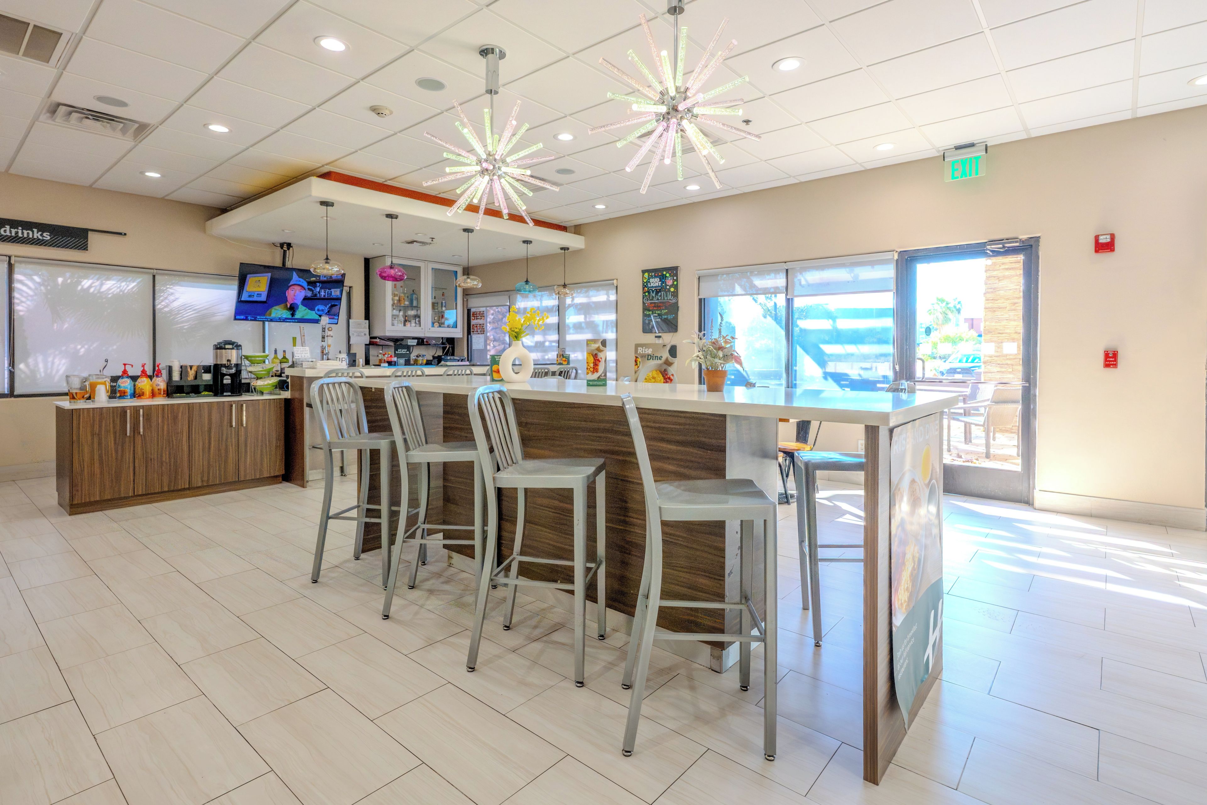 A modern bar area with a counter, bar stools, and a television screen.