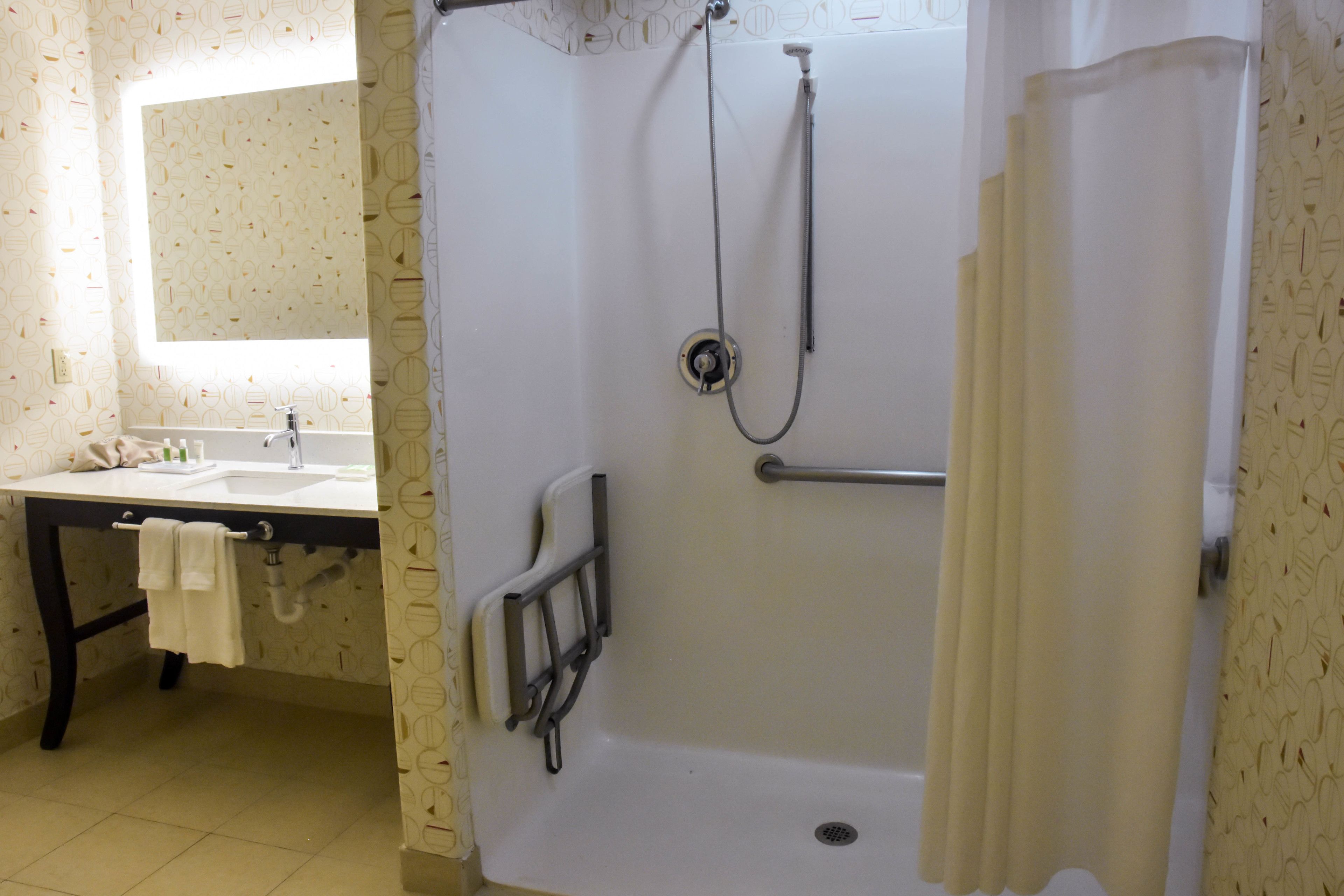 A bathroom with a bathtub, a sink, a mirror, and a towel rack.
