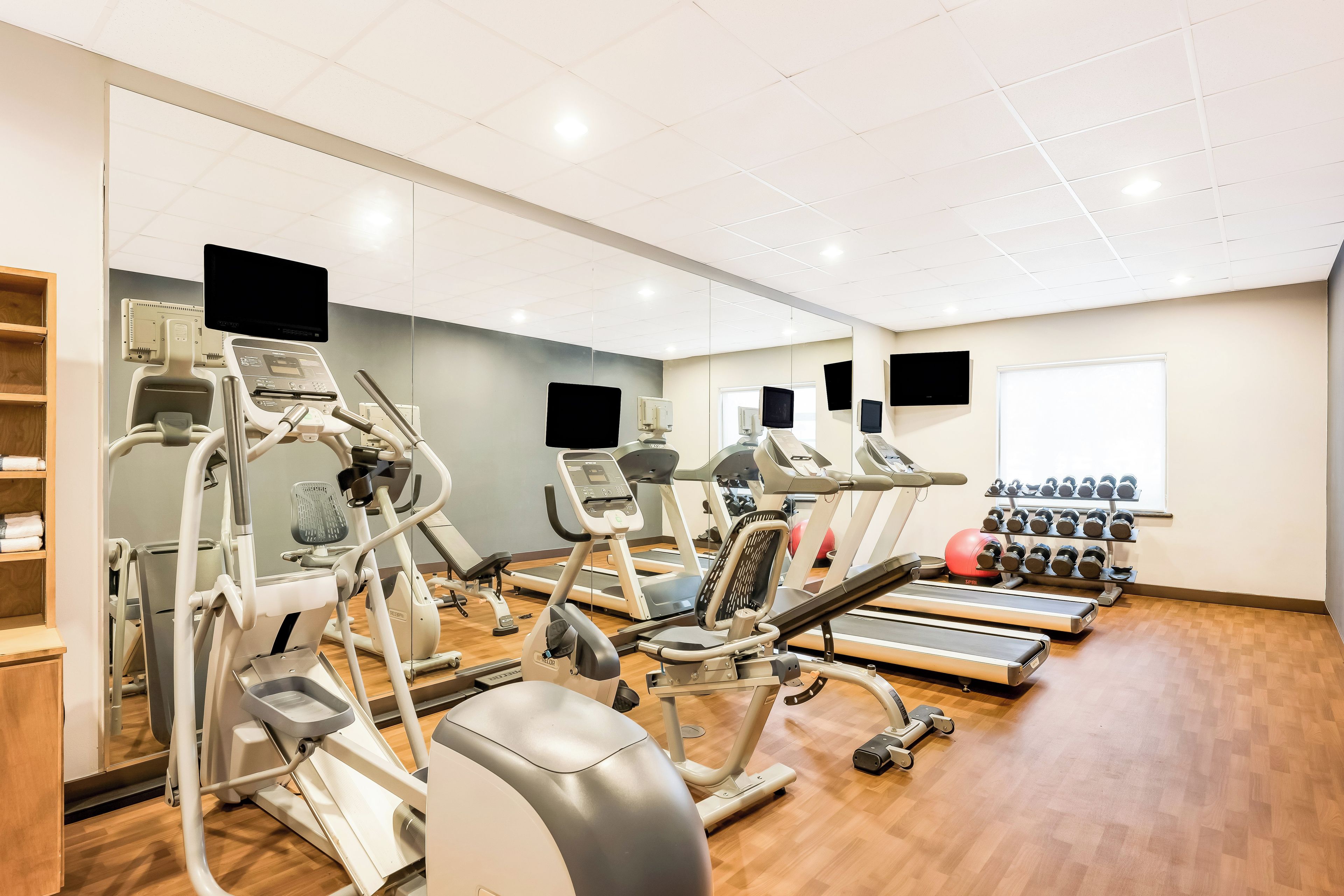 Une salle de sport équipée de tapis de course, de vélos elliptiques et de supports pour les poids.
