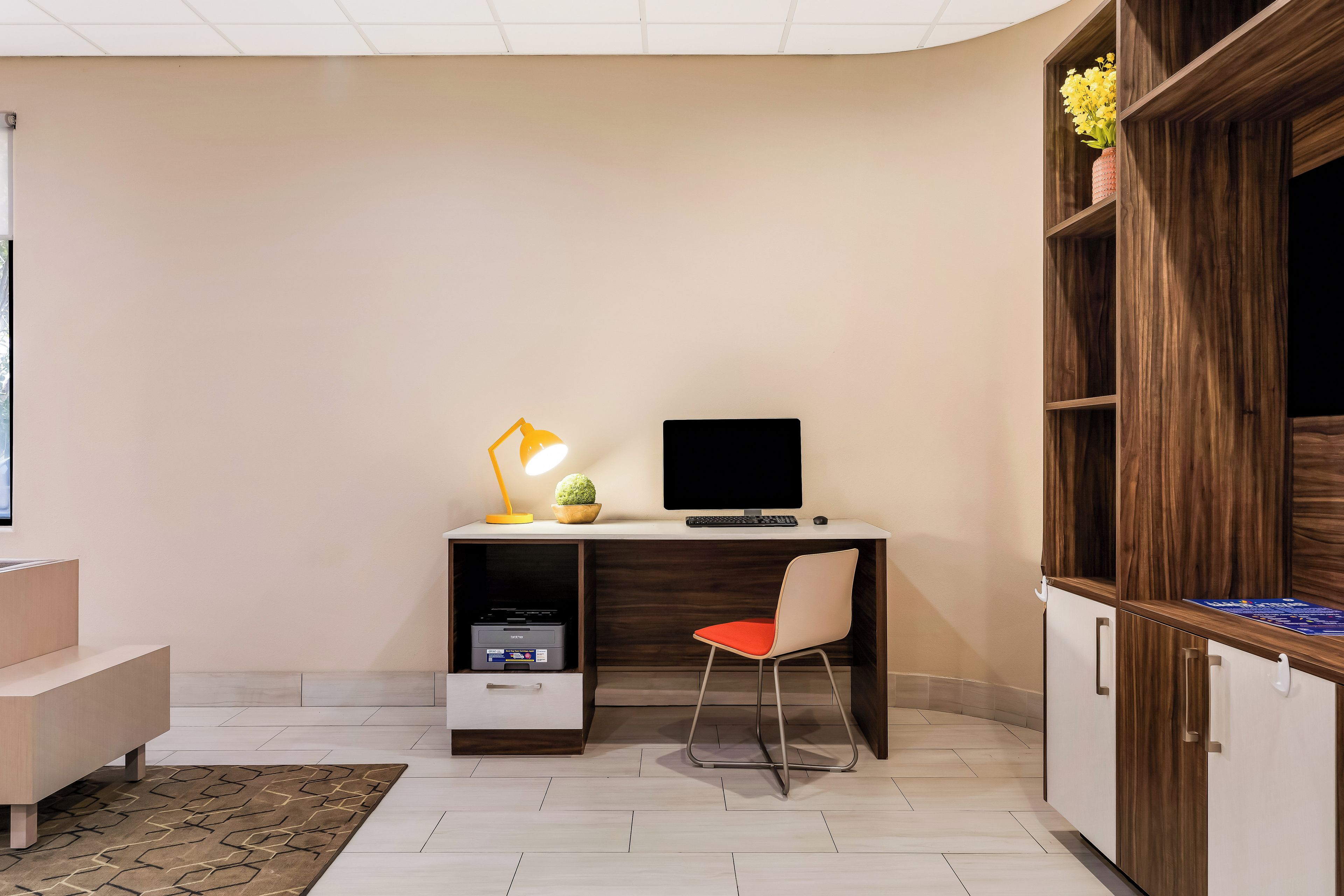 A modern office space with a desk, computer, chair, and a lamp.