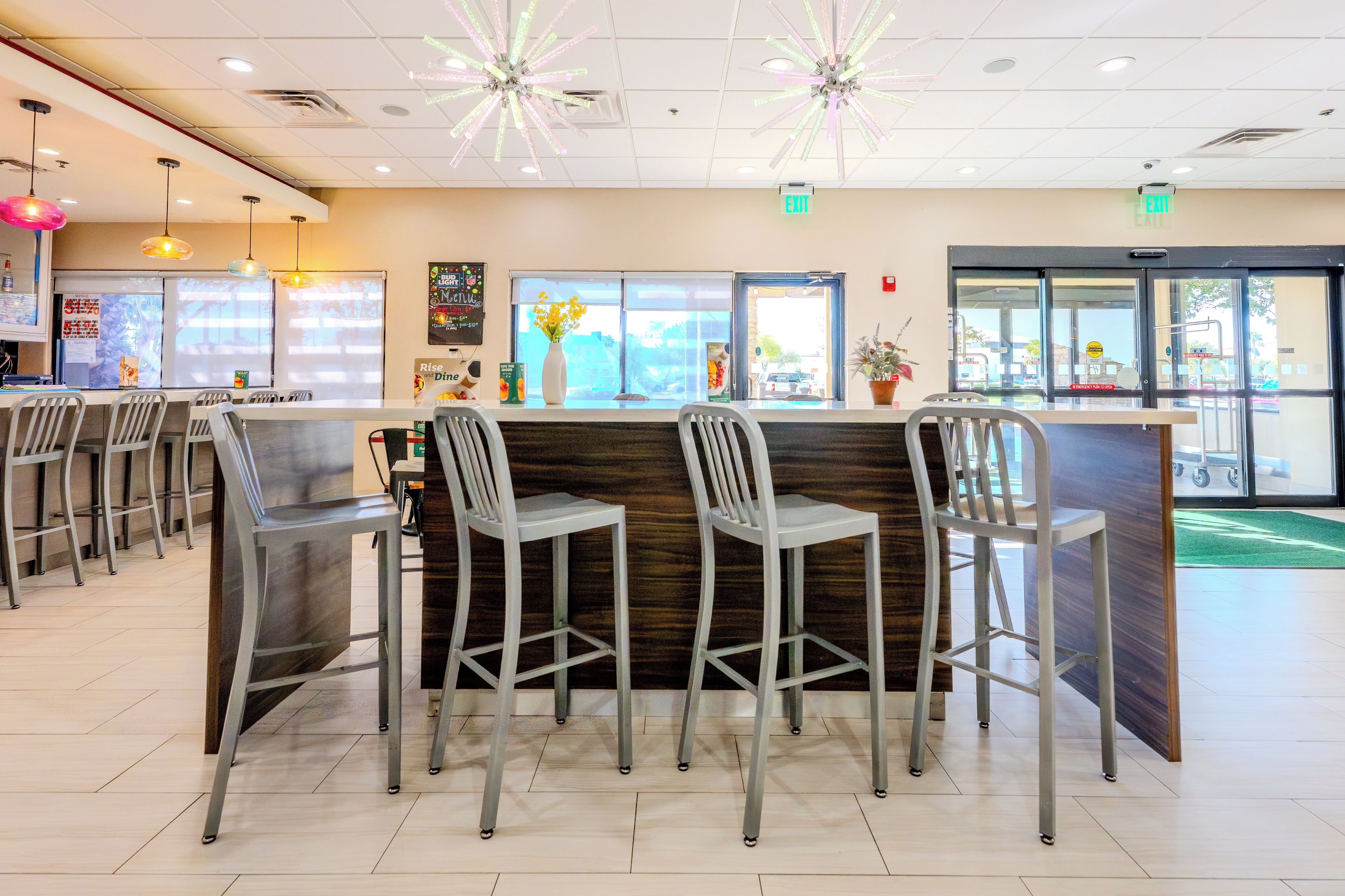 A restaurant interior with a bar area, multiple seating arrangements, and a view of the outside through the windows.