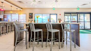 A restaurant interior with a bar area, multiple seating arrangements, and a view of the outside through the windows.