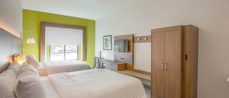 A hotel room with two beds, a desk, a wardrobe, and a window with a view.