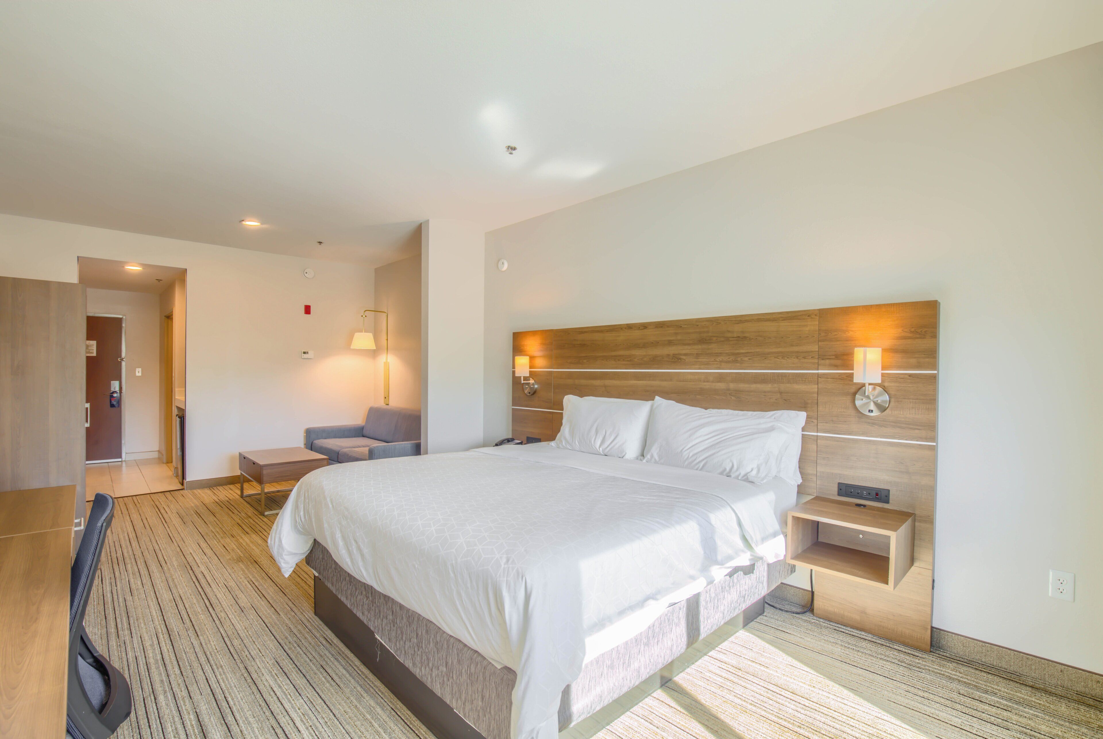 Une chambre d’hôtel avec un grand lit, des tables de chevet, un bureau et une chaise.