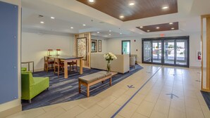 A lobby with a reception desk, seating area, and a large glass door entrance. - Holiday Inn Express & Suites Gulf Shores by IHG (Gulf Shores)