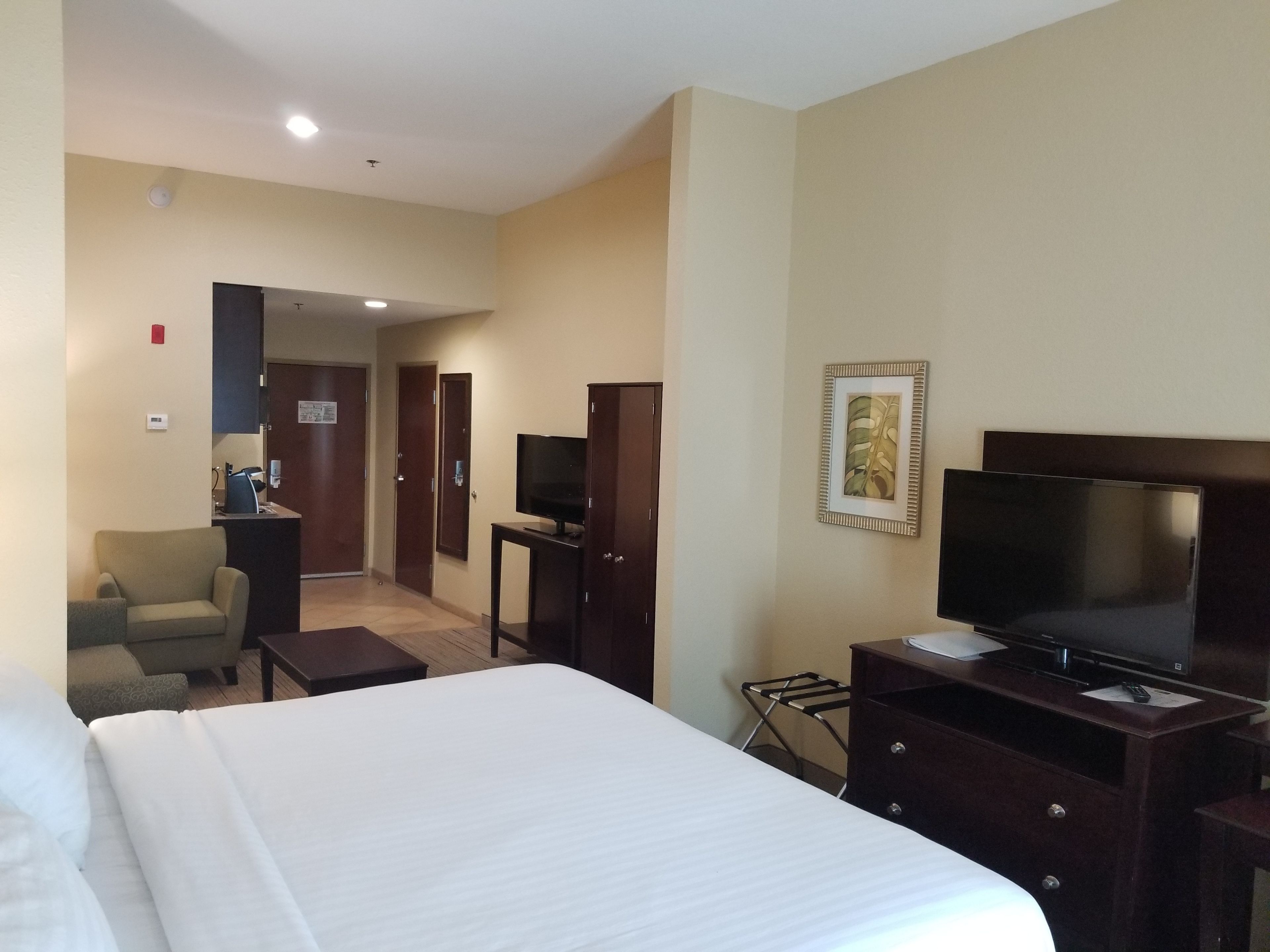 A hotel room with a bed, a TV, a desk, a chair, and a wardrobe.