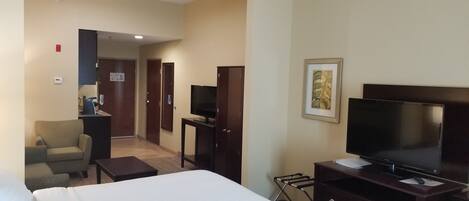 A hotel room with a bed, a TV, a desk, a chair, and a wardrobe.