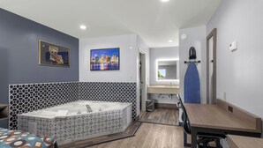 A modern bathroom with a large bathtub, a wooden vanity, and a cityscape painting on the wall. - Express Inn and Suites (Westwego)