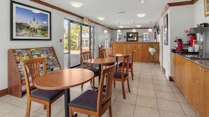 A restaurant with wooden tables and chairs, a coffee machine, and a menu board. - Express Inn and Suites (Westwego)