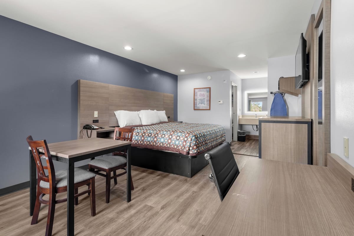 Quarto de hotel pequeno com cama, escrivaninha e cadeira.