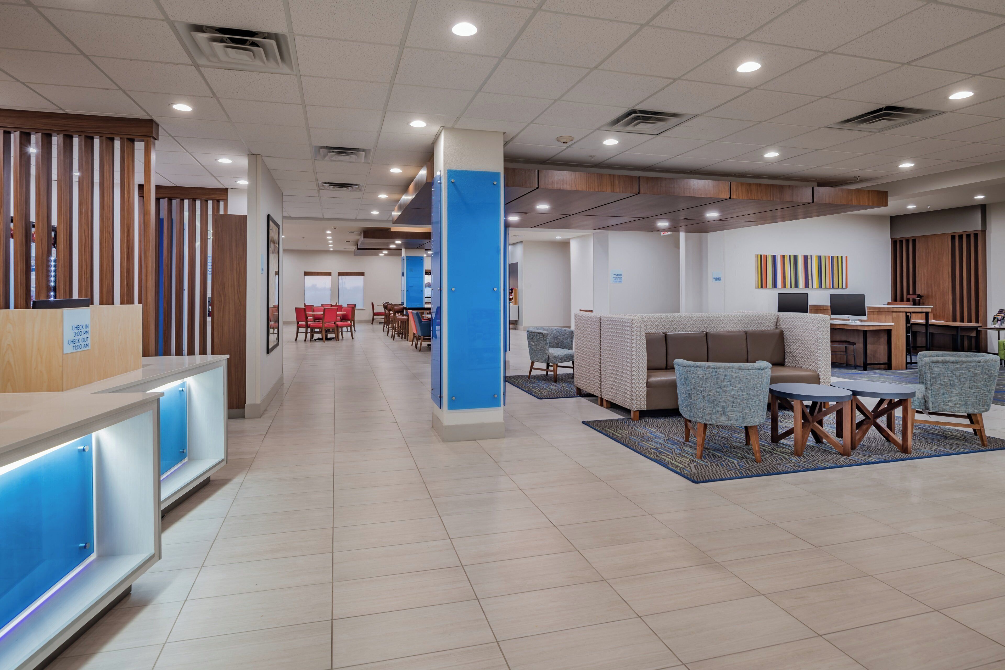 A hotel lobby with a reception desk, seating area, and a counter with a blue accent.