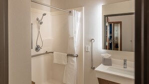 A modern bathroom with a shower, grab bar, and a sink with a mirror. - Holiday Inn Express & Suites N Waco Area - West by IHG (West)