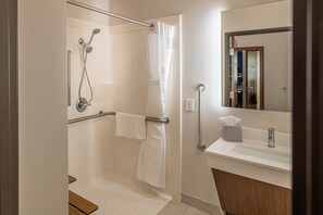 A modern bathroom with a shower, grab bar, and a sink with a mirror. - Holiday Inn Express & Suites N Waco Area - West by IHG (West)