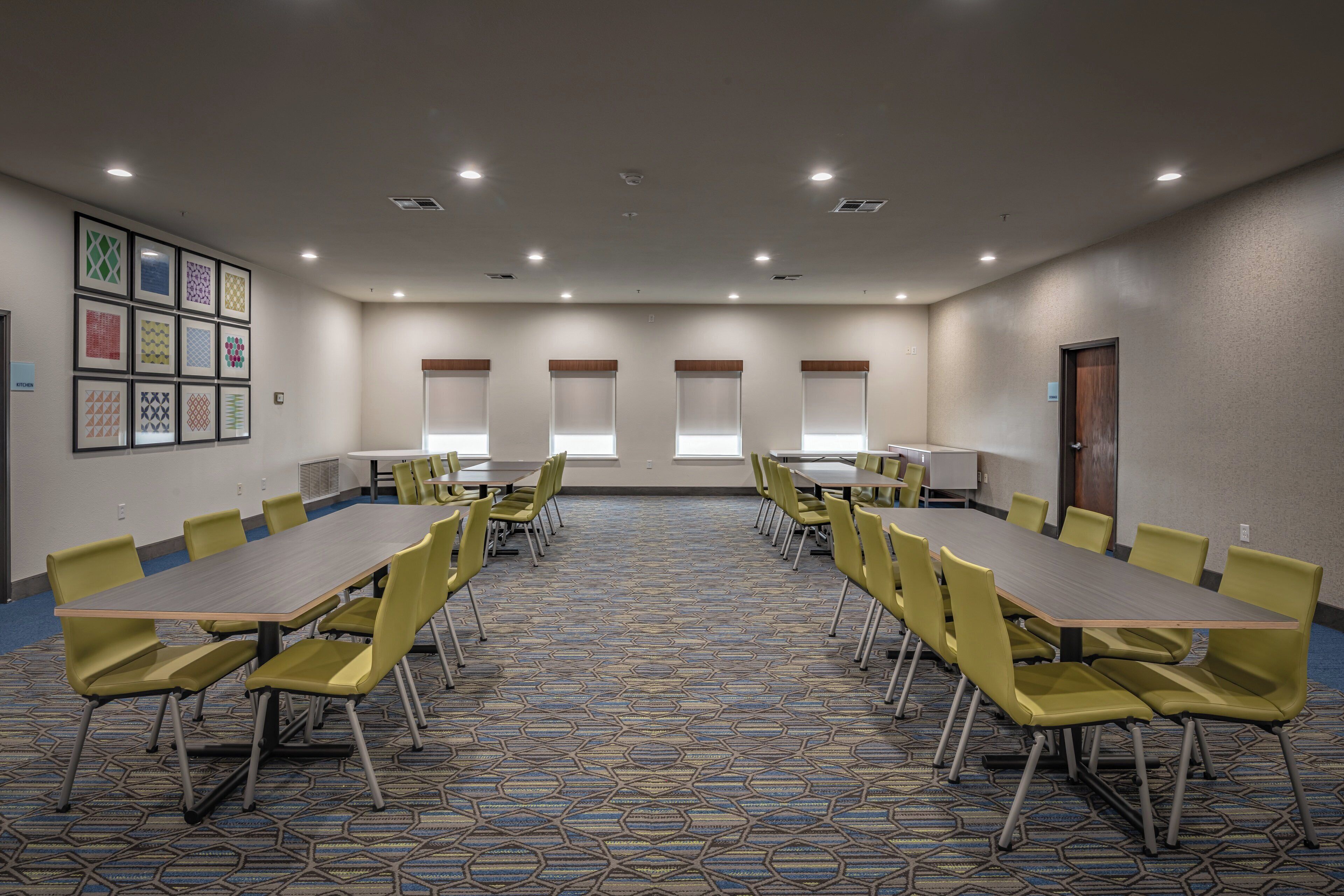 Une salle de conférence avec une longue table et des chaises, une moquette à motifs et un mur orné de tableaux.