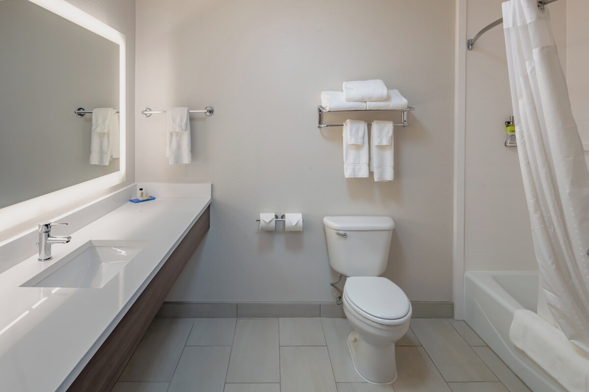 A bathroom with a sink, toilet, and shower curtain.