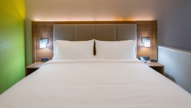 A hotel room with a large bed, two bedside tables, and wall-mounted lamps. - Holiday Inn Express & Suites N Waco Area - West by IHG (West)