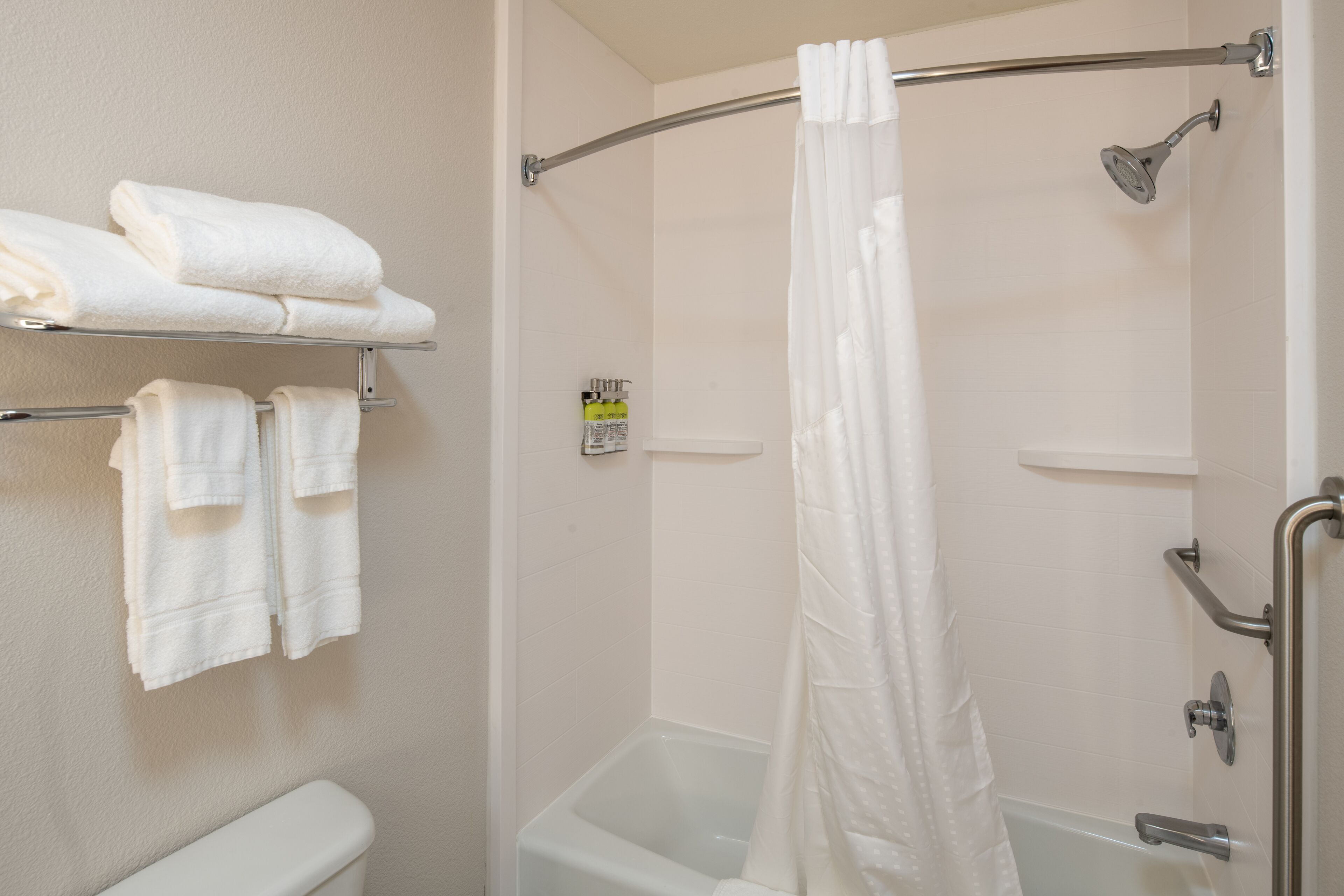 Un baño con ducha, inodoro y toallero con toallas dobladas.