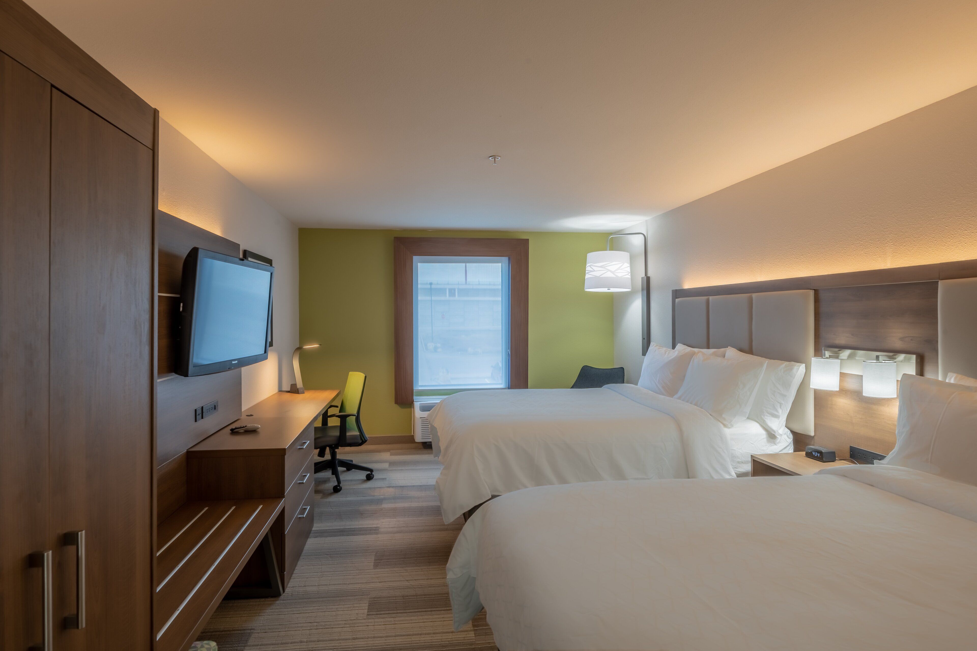 A hotel room with two beds, a TV, a desk, and a chair.