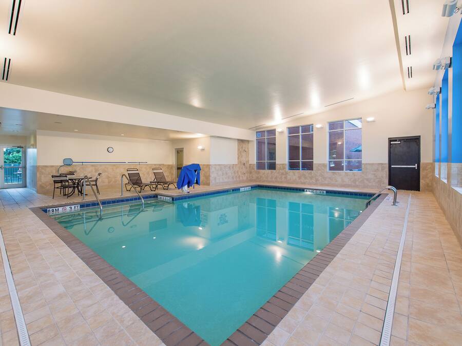 An indoor swimming pool with clear water, tiled walls, and a tiled floor.