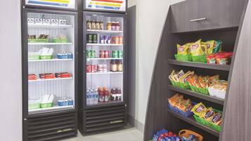 A vending machine with snacks and drinks, and a shelf stocked with chips and other snacks.