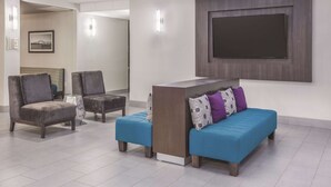 Um lobby moderno com um balcão de recepção, dois sofás e duas poltronas.