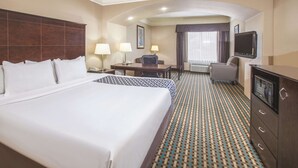 Quarto de hotel com uma cama grande, uma escrivaninha com cadeira, televisão e banheiro.