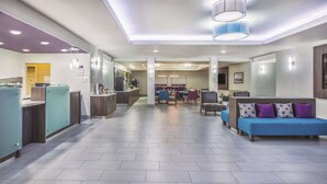 Um saguão moderno de hotel, com balcão de atendimento, área de estar e kitchenette.