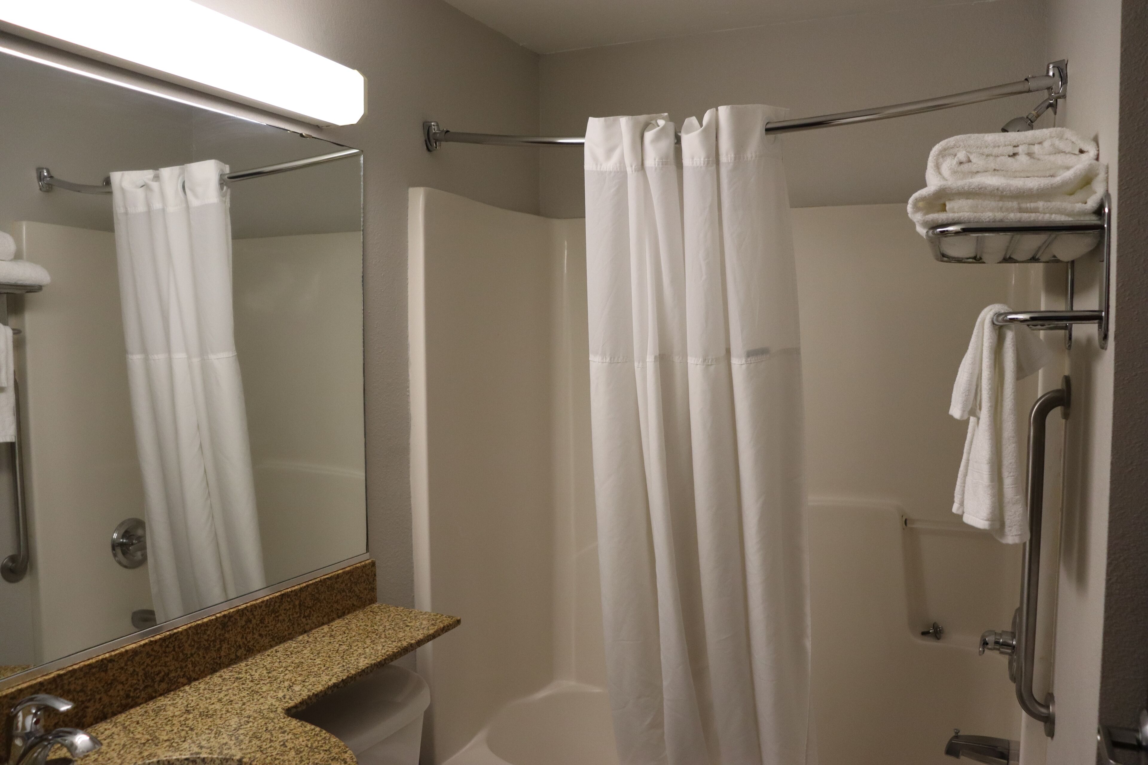 A modern bathroom with a shower, a sink, and a towel rack.