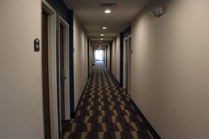 Pasillo de hotel con piso de diseño ajedrezado, puertas a ambos lados y un letrero que indica el número de habitación 403.