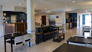 A modern hotel lobby with a reception desk, seating area, and kitchenette. - Microtel Inn & Suites by Wyndham Columbus/Near Fort Benning (Columbus)