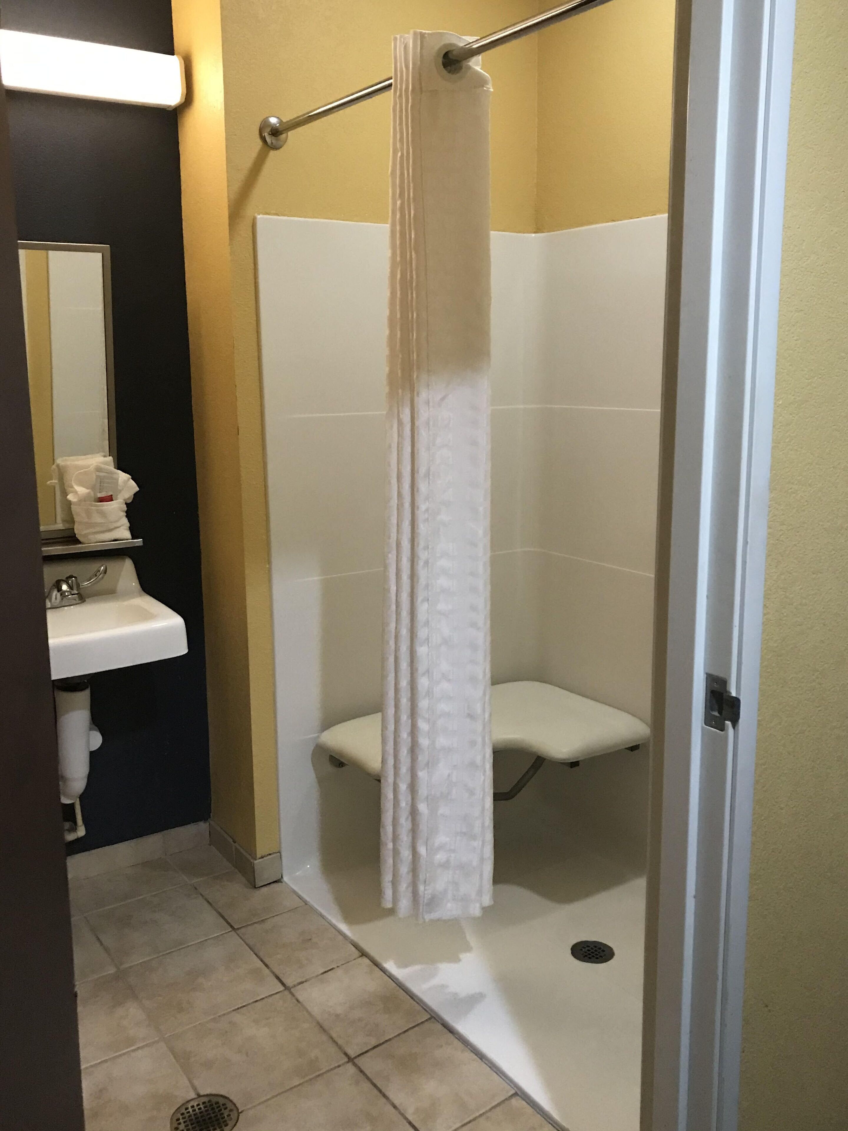 Une salle de bain avec une douche, un lavabo et un miroir.