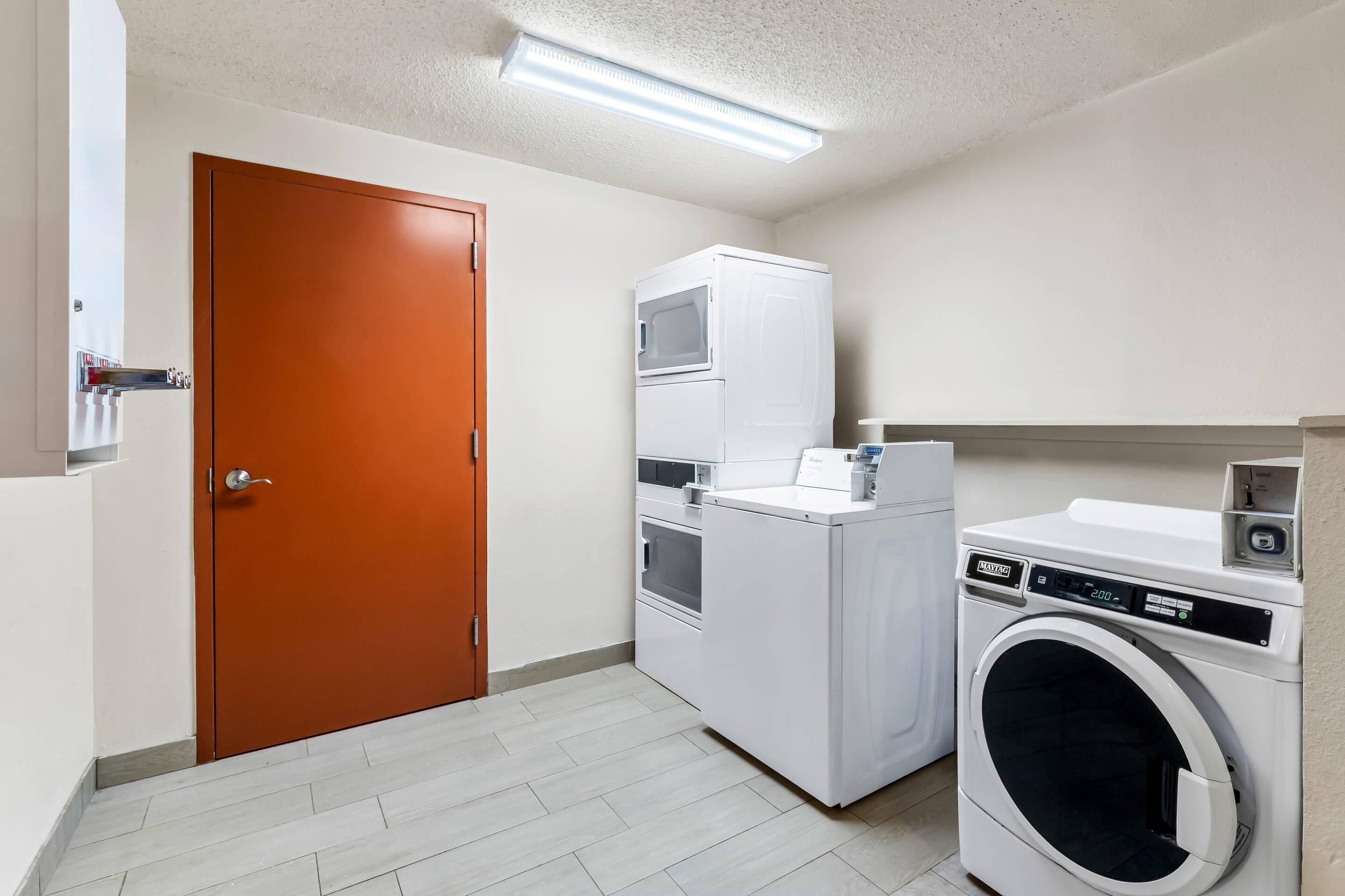 A laundry room with a washing machine, dryer, and stacked washer-dryer unit.
