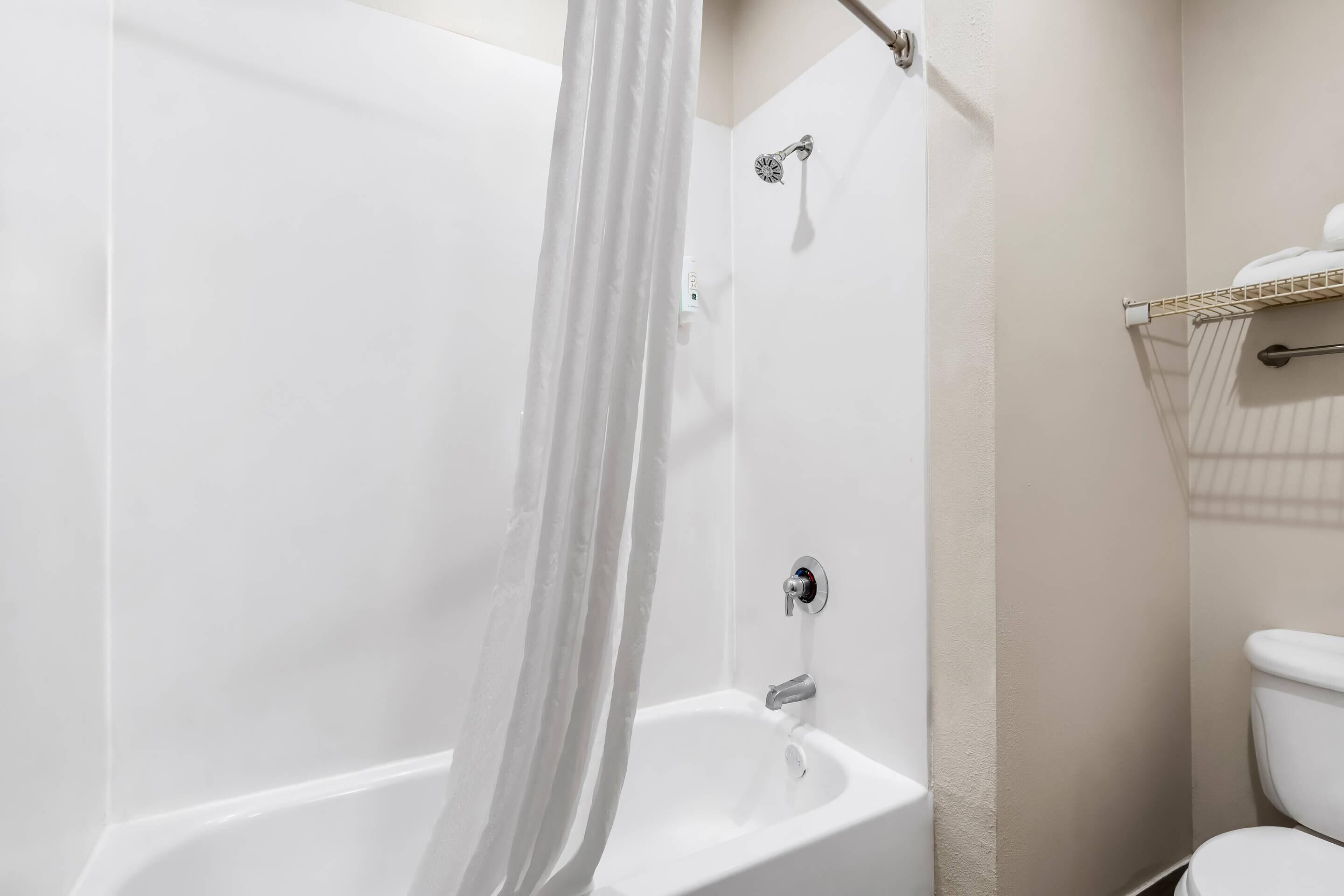 A bathroom with a bathtub, shower, toilet, and a towel rack.