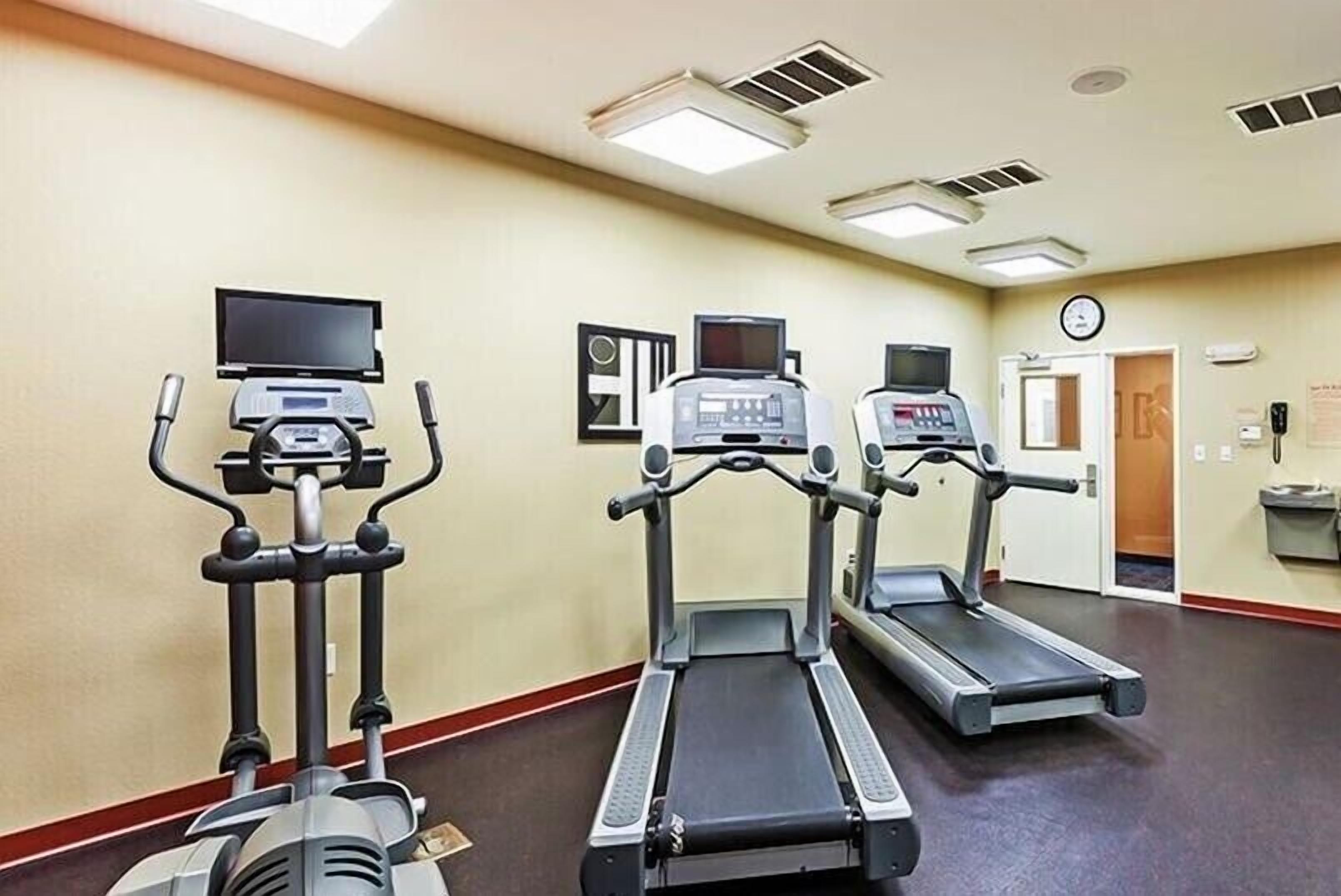 Un gimnasio con cintas de correr y una máquina elíptica.