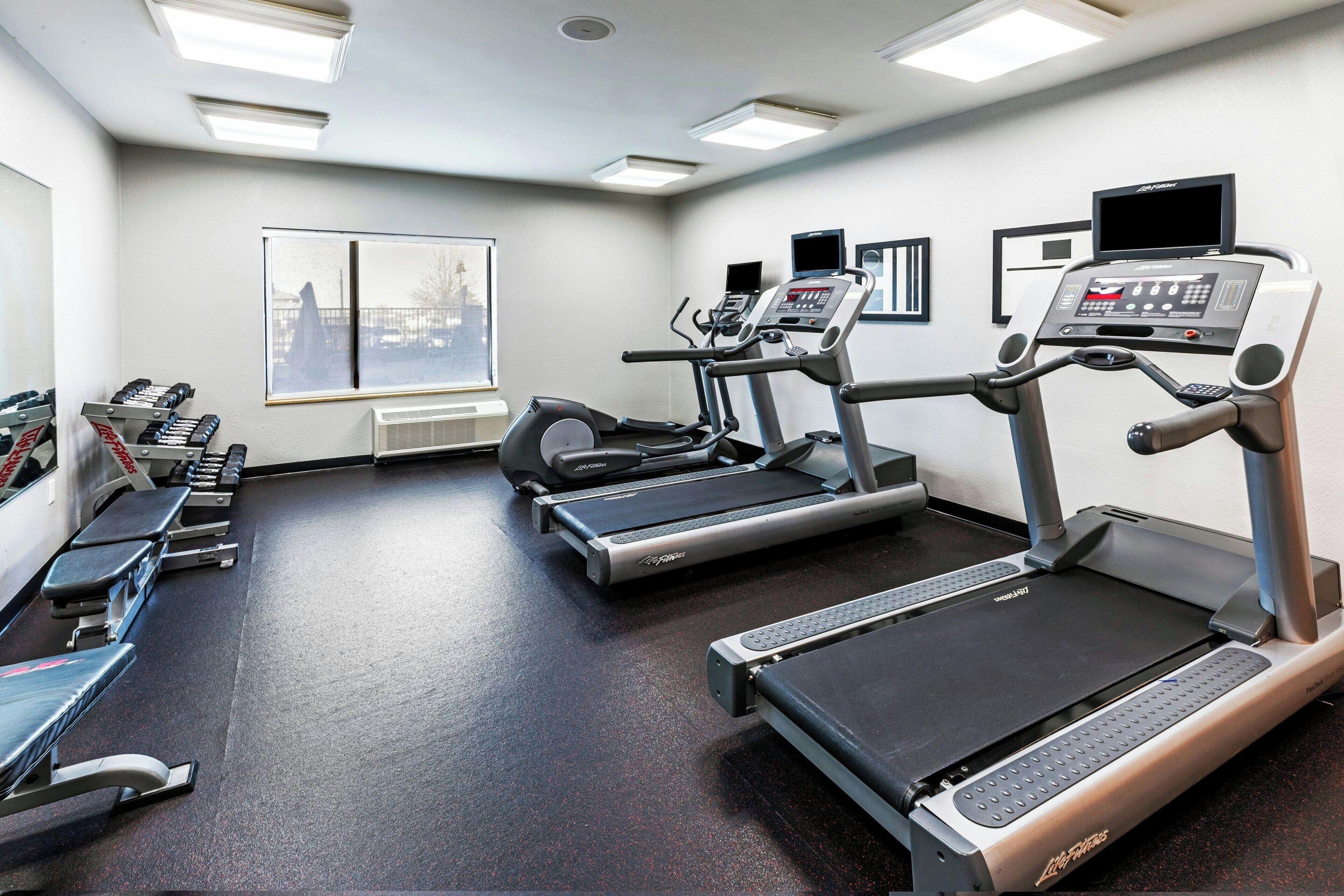 Un gimnasio con cintas de correr, elípticas y bancos de pesas.