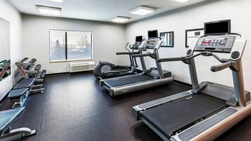 A gym with treadmills, elliptical machines, and weight benches.