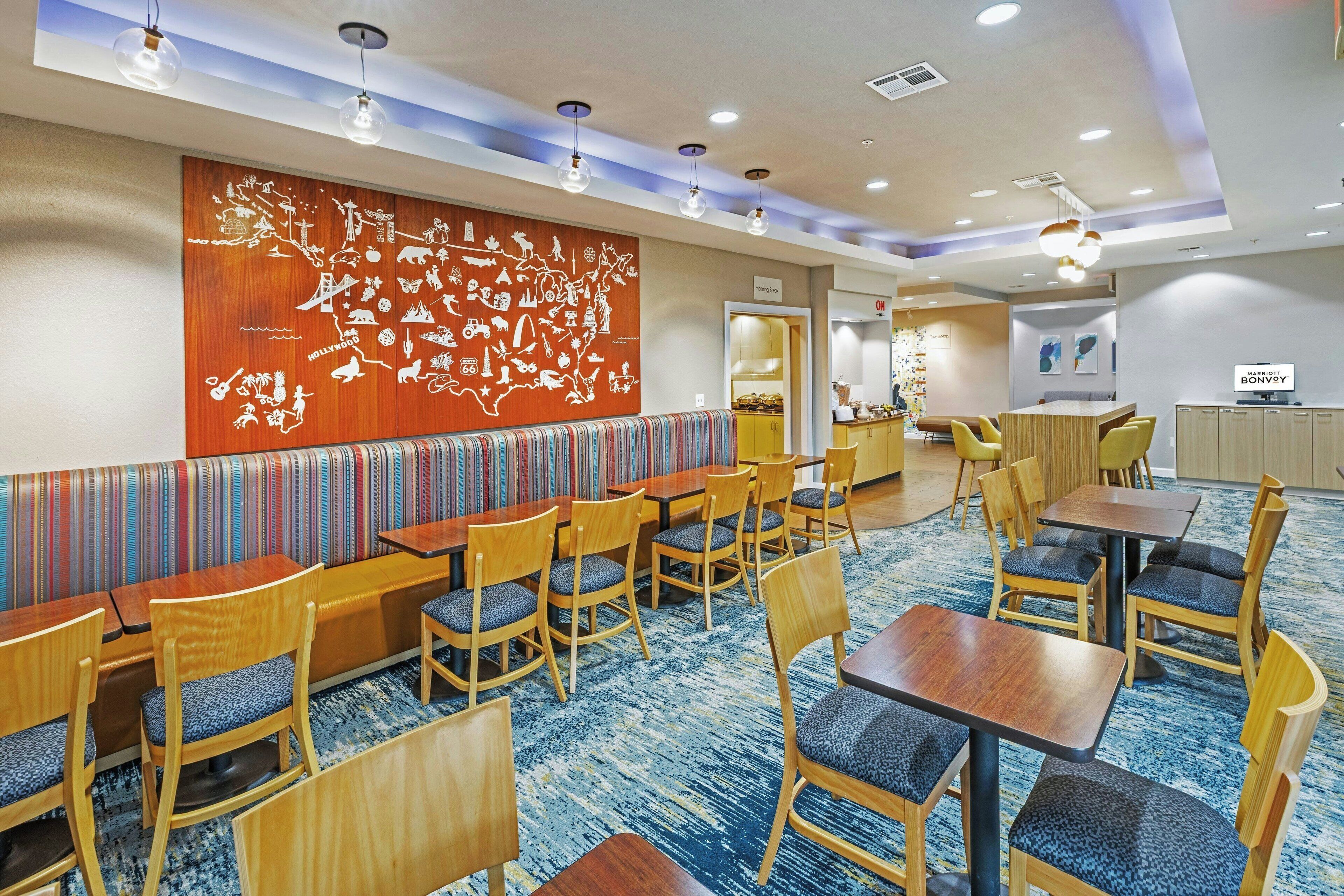 A hotel lobby with a large wall mural, multiple seating areas, and a reception desk.