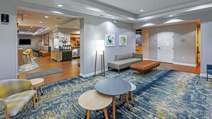 Een moderne woonkamer met een bank, twee ronde tafels en een salontafel. In de achtergrond is een keuken met een eettafel en stoelen te zien.