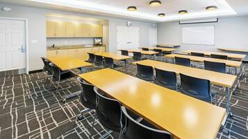 A classroom with rows of desks, a whiteboard, and a kitchenette area.
