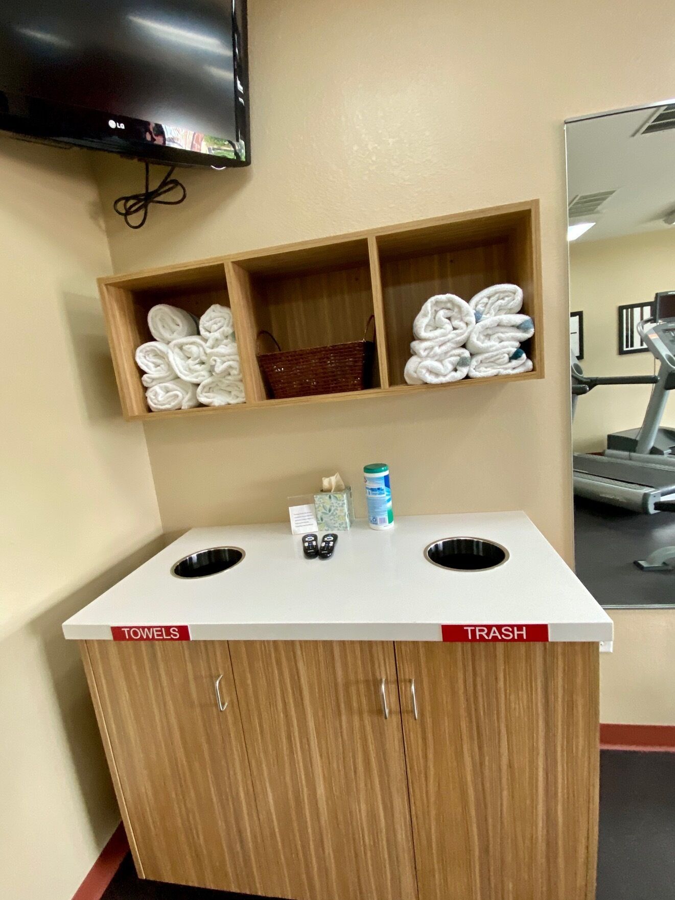 A hotel bathroom with a towel rack, a trash bin, and a small shelf with toiletries.
