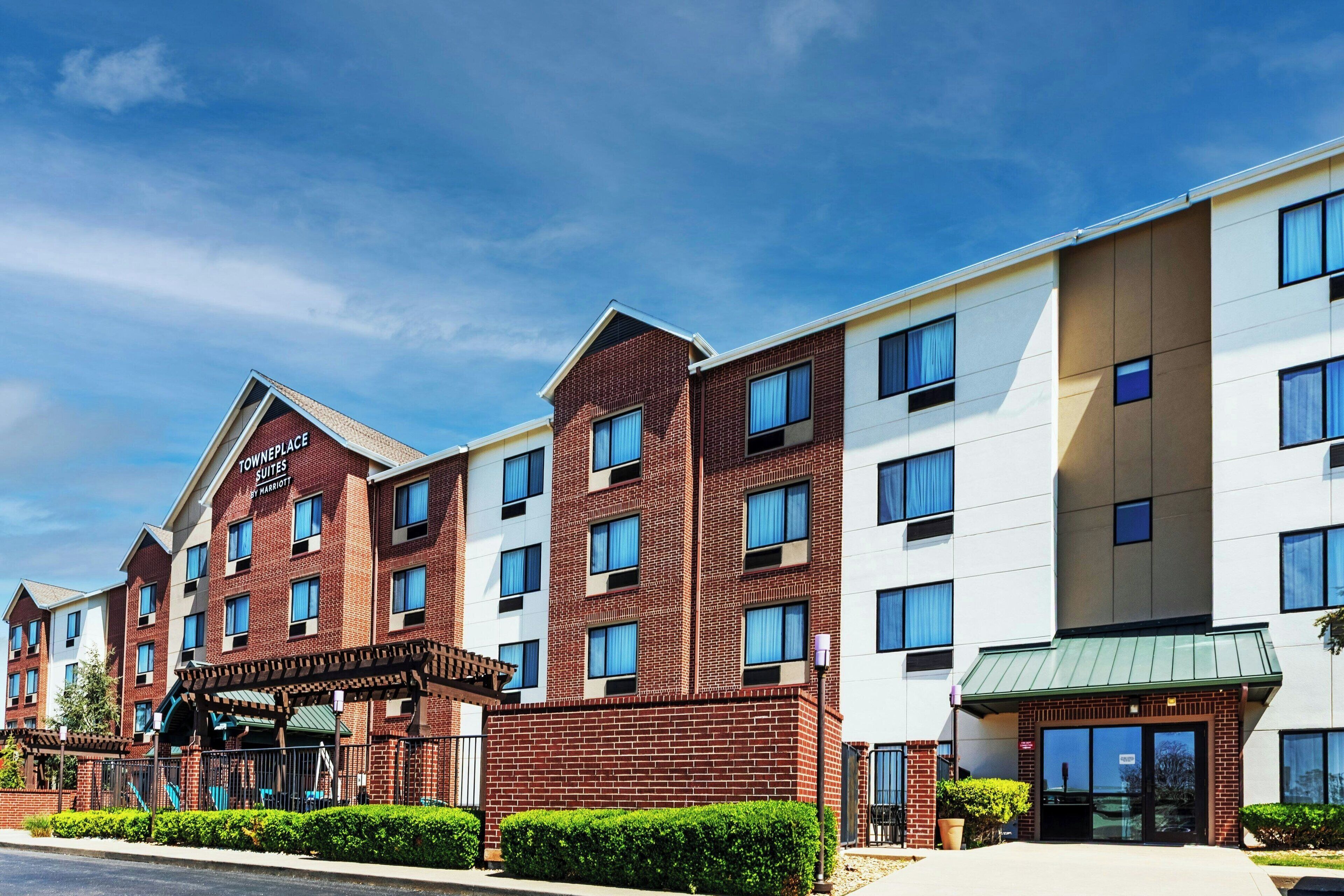 A multi-story hotel with a brick facade, large windows, and a covered entrance area.