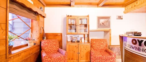 A wooden interior with two patterned armchairs, a bookshelf, and a reception desk labeled "OY TOWNH".