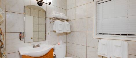 A bathroom with a sink, mirror, toilet, and towel rack.